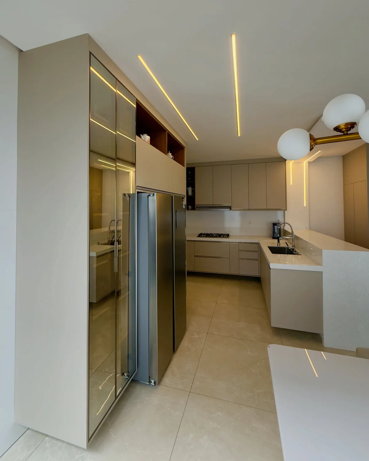 Cozinha planejada em tom areia com iluminação embutida, executada pela Versus